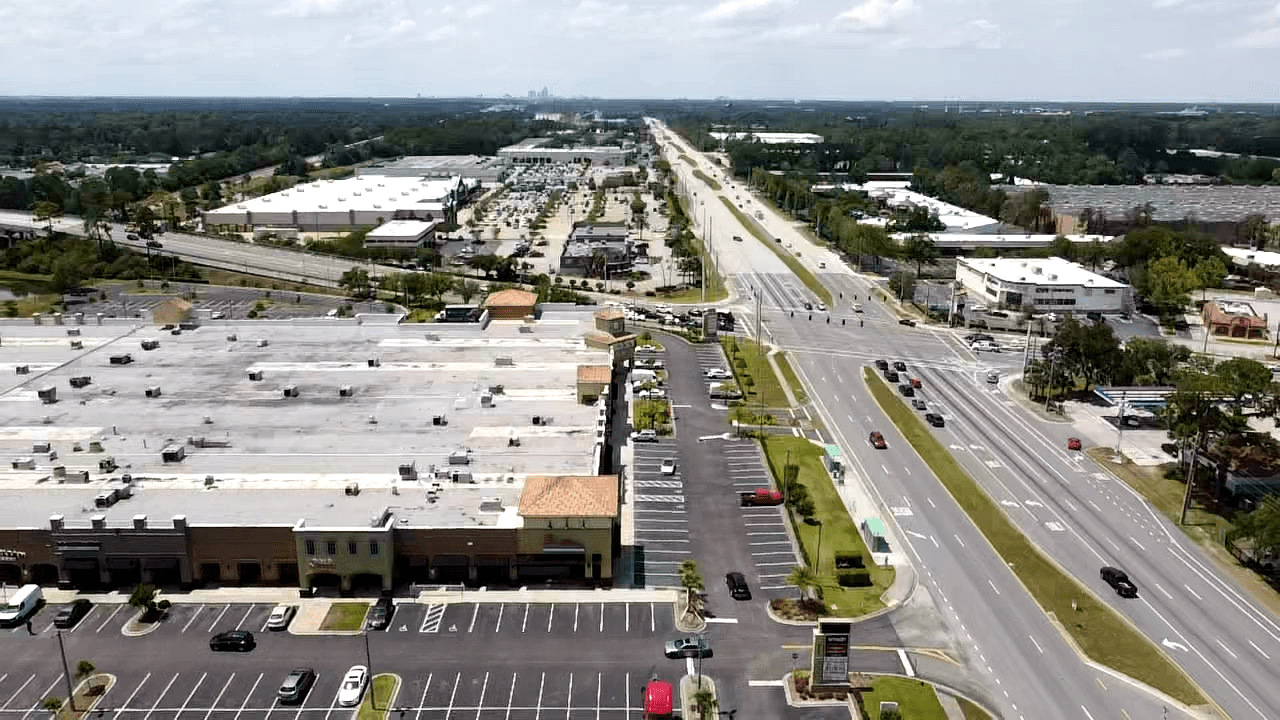 An aerial view of a one-story retail center and intersection.