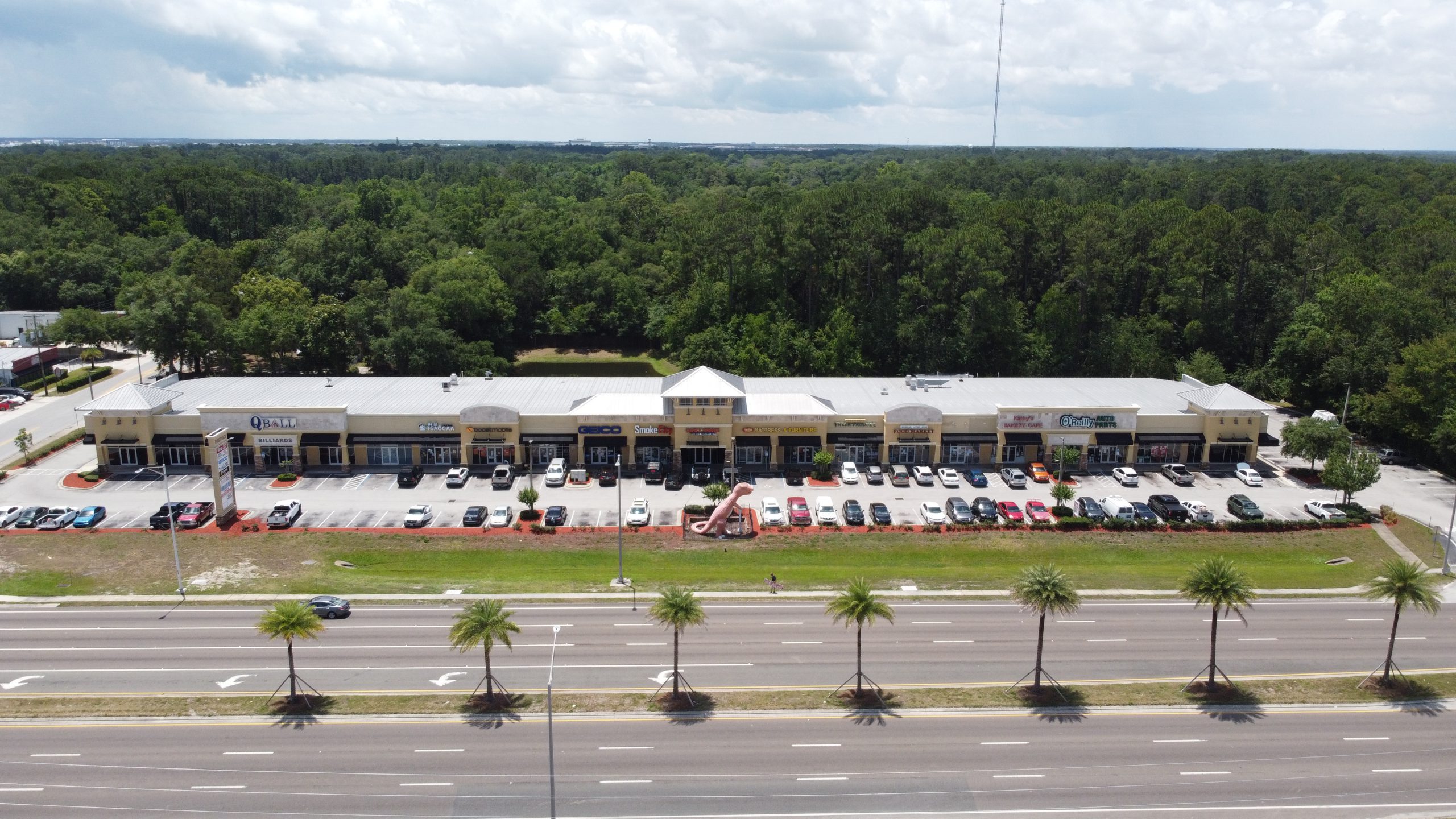 An aerial view of a one-story retail center & road.